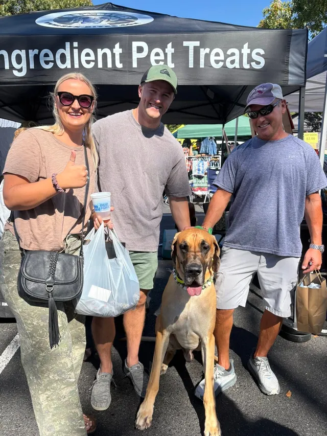 Customers giving a thumbs up next to Rex in front of the Rex Bites tent